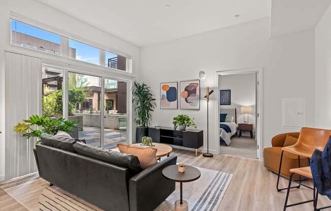 A living room with a black couch and a wooden floor.