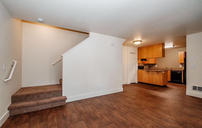 a living room with a staircase and a kitchen in the background