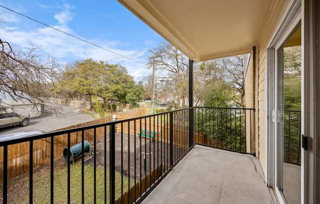 A balcony with a black railing and a green trash can.