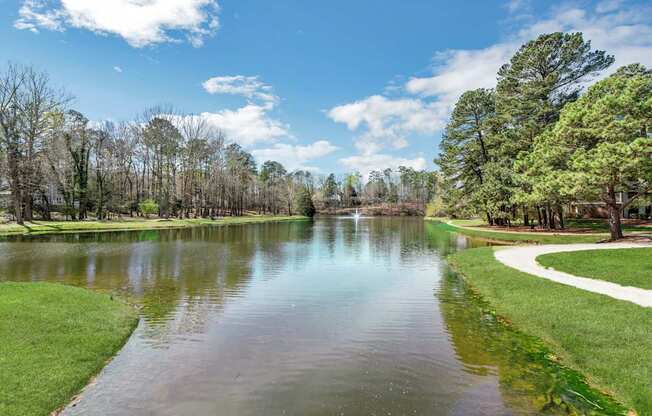 A serene lake surrounded by trees and a clear sky.