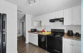 A kitchen with black appliances and white cabinets.