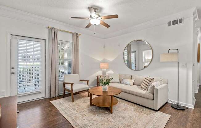 A living room with a white couch, a wooden coffee table, and a ceiling fan.