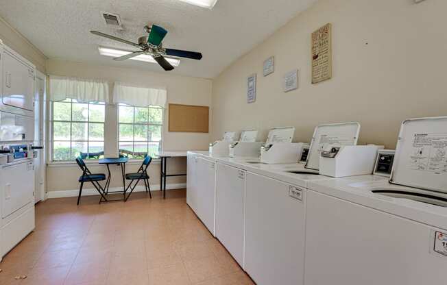 Laundry room with plenty of washers and dryers and seating  at Arbors Of Cleburne, Texas