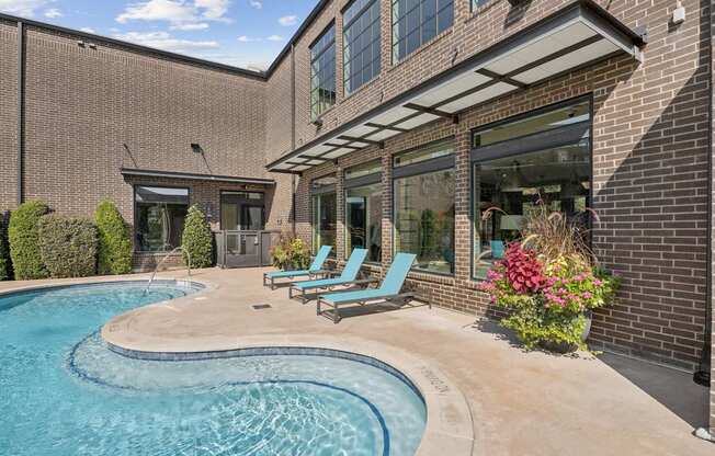 A small pool in a backyard with a building in the background.