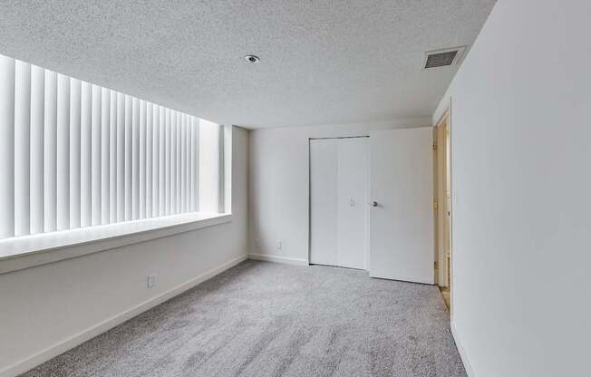 A room with a carpeted floor and a window with blinds at Lowertown Commons Apartments, St. Paul