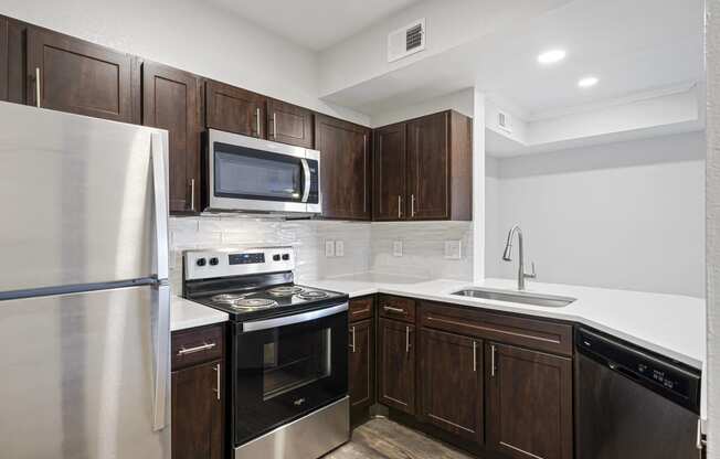 a kitchen with dark wood cabinets and stainless steel appliances