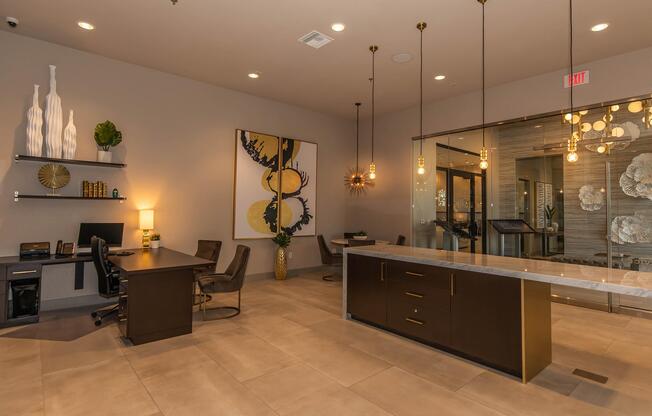 Modern lobby area featuring a reception desk, stylish office furniture, and decorative wall art. Soft lighting from pendant fixtures creates an inviting atmosphere. The space includes plants and shelving with decorative items, highlighting a contemporary design aesthetic.