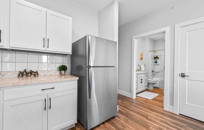 A kitchen with white cabinets and a stainless steel refrigerator.