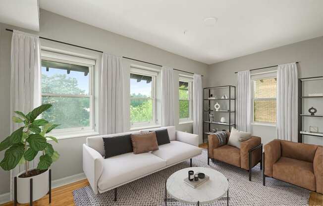 a living room with a white couch and two brown chairs