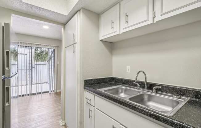 a kitchen with white cabinets and a sink and a window