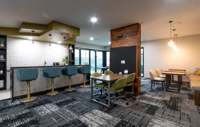 a lounge area with tables and chairs and a bar with stools at 310 at Nulu Apartments-Student, Louisville, 40202