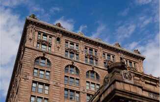 A tall brown building with many windows and decorative stonework at The Pennsylvanian Apartments, Pittsburgh, Pennsylvania