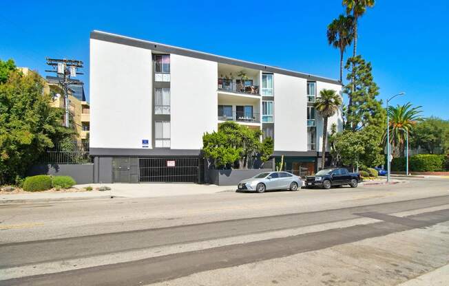 a white apartment building with cars parked in front of it