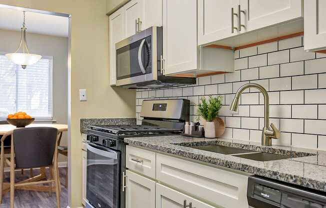 a kitchen with white cabinets and black appliances