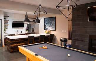 A pool table is in the middle of a room with a fireplace and a TV.
