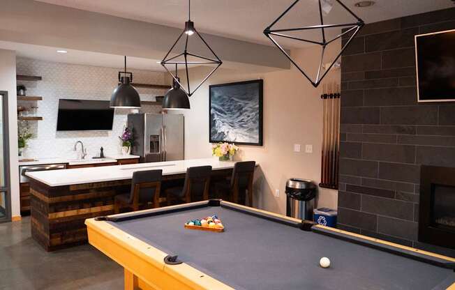 A pool table is in the middle of a room with a fireplace and a TV.