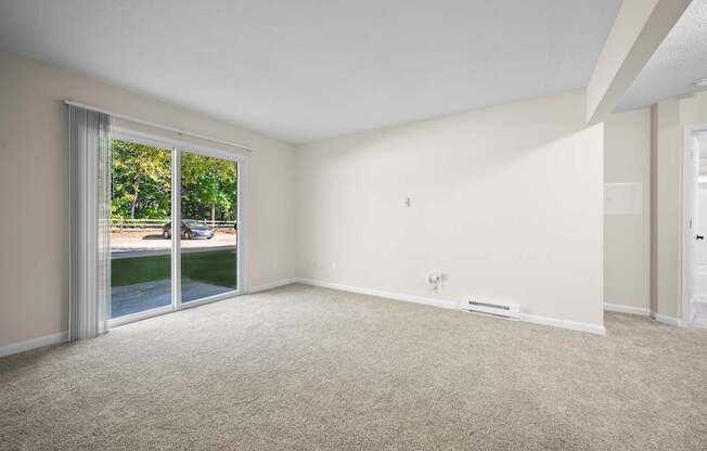 A room with a carpeted floor and a sliding glass door leading to a patio.