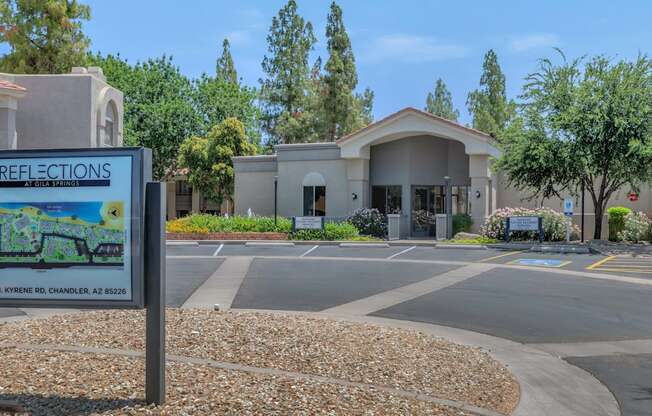 A sign for Reflections at the entrance of a building with a parking lot in front.