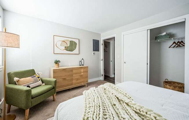 A bedroom with a bed, chair, and wardrobe.