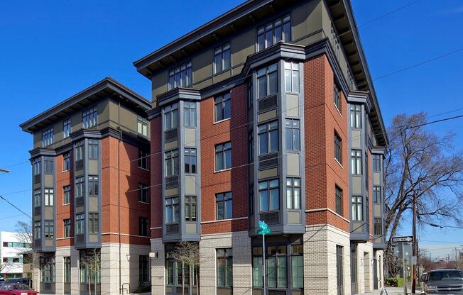 A red car is parked on the street in front of a multi-story building.