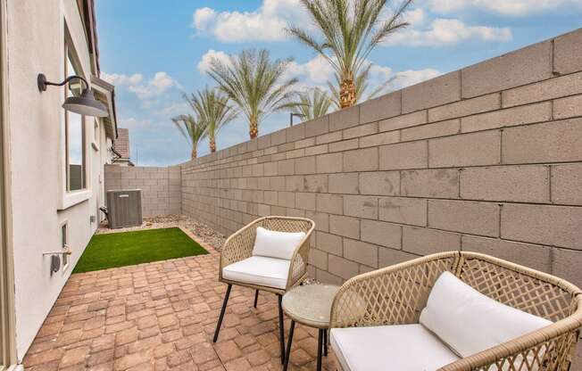 a patio with two chairs and a table next to a wall