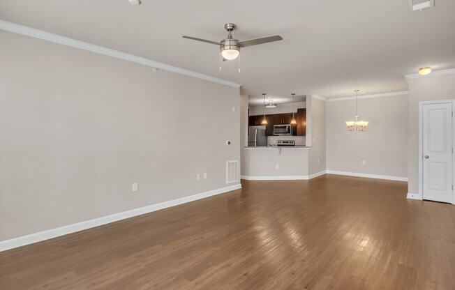 an empty living room with wood floors and a ceiling fan