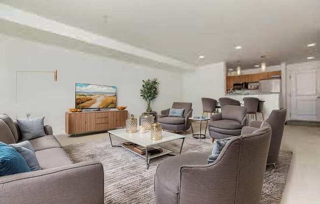A living room with grey couches and a painting on the wall.