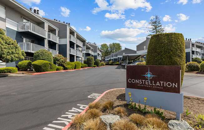 A sign for Constellation Apartments is in the foreground of a road.