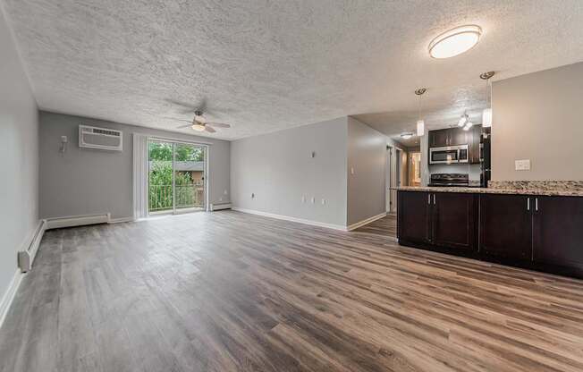 A spacious room with wood flooring and a ceiling fan.