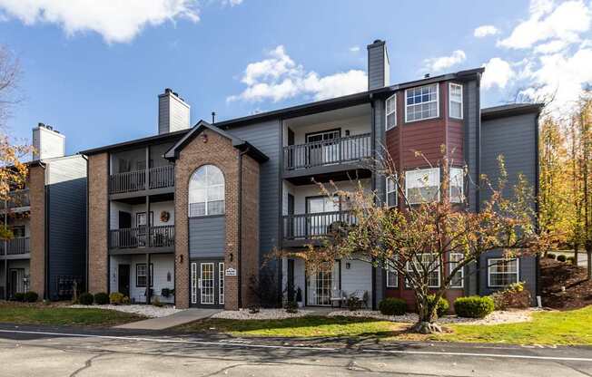 A large apartment building with a balcony and a tree in front.