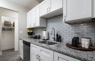a white kitchen with marble counter tops and white cabinets at The Heights Apartments, Ohio