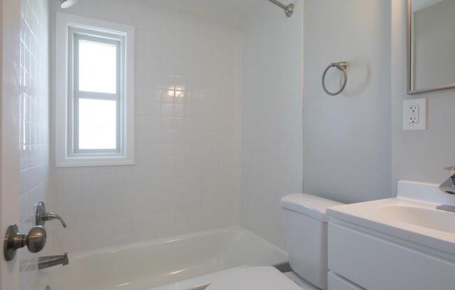 A white bathroom with a tub, toilet, and sink.