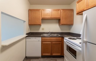 This is a photo of a kitchen with honey oak cabinets and white appliances in a 560 square foot 1, 1 bath apartment at Park Lane Apartments in Cincinnati, OH.