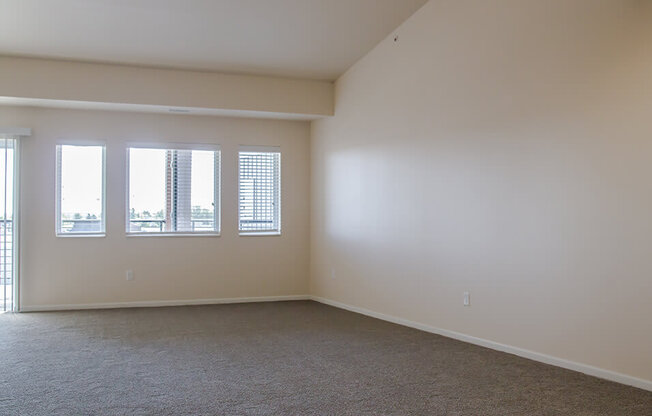 a bedroom with three windows and a carpeted floor