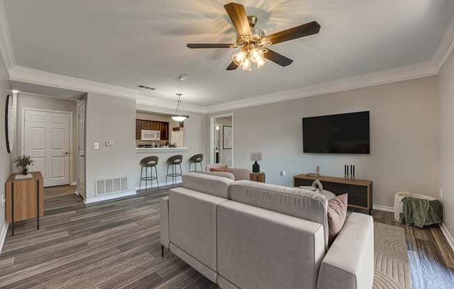 A living room with a grey couch and a ceiling fan.