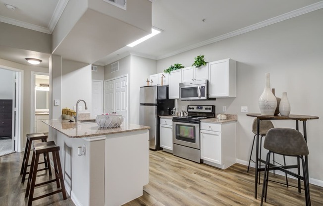a kitchen with white cabinets and appliances and a bar with stools