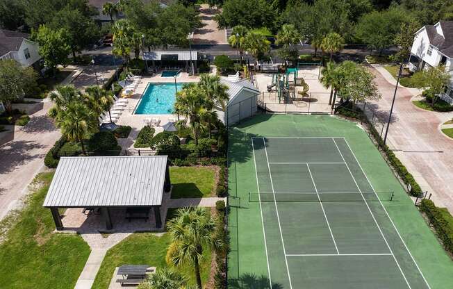 an aerial view of a tennis court and a pool in the backyard of a house