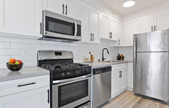 a kitchen with white cabinets and stainless steel appliances