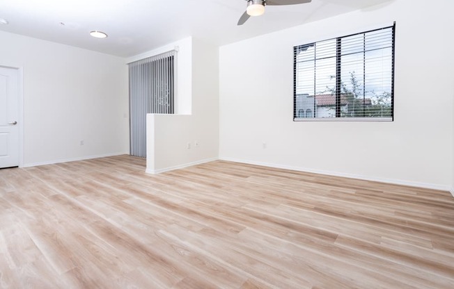 an empty living room with wood flooring and a window