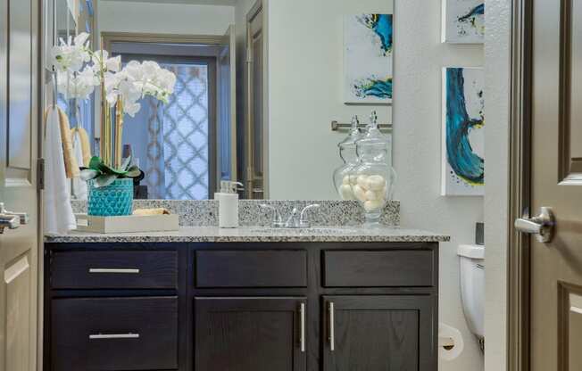 This is the bathroom with a single sink and mirror and lighting and cabinets