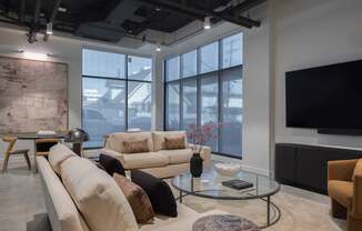 A living room with a large window, a couch, a coffee table, and a television.