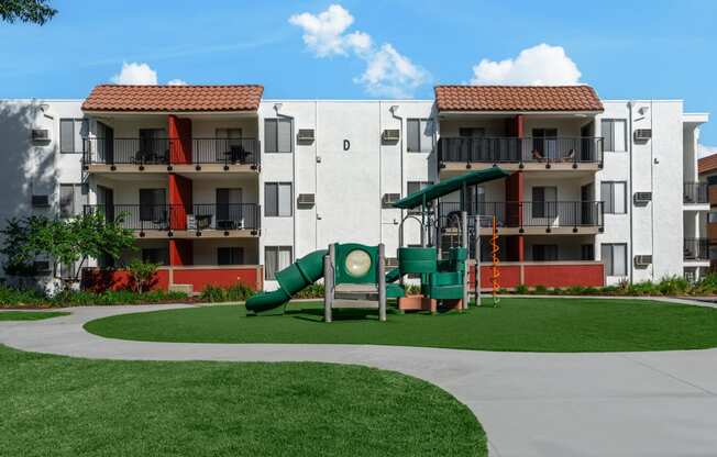 a playground in an apartment building with a large green slide