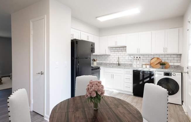 a kitchen and dining room with white cabinets and black appliances at Carrolton in Carrolton, GA 30117