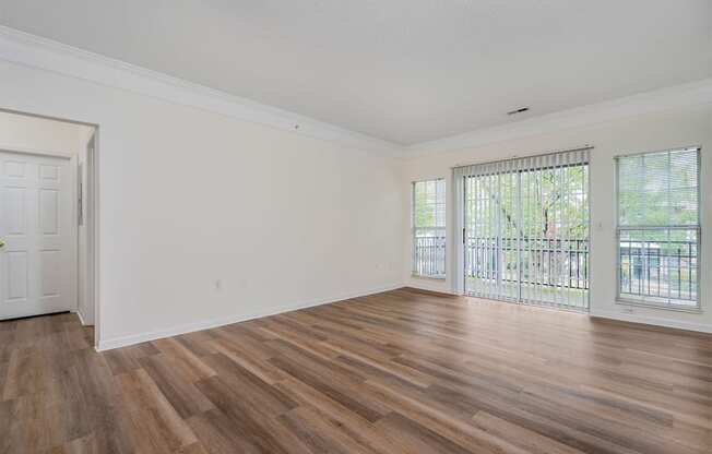 an empty living room with wood flooring and a balcony