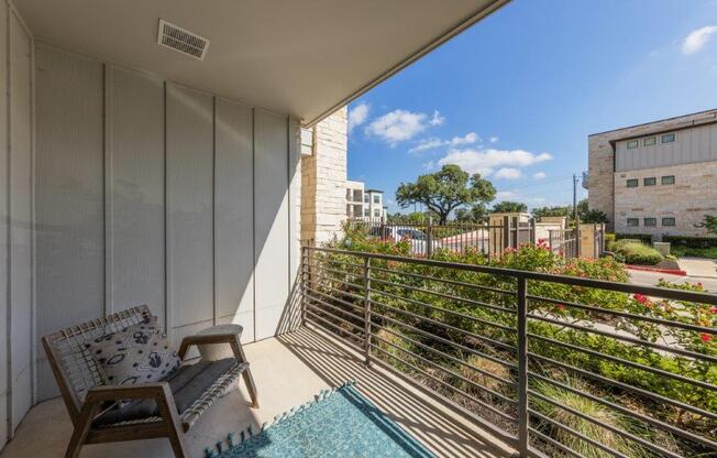 A balcony with a chair and a table with a cushion and a tablecloth on it.