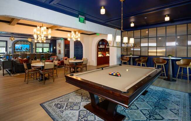 A pool table is in the middle of a room with a blue rug.