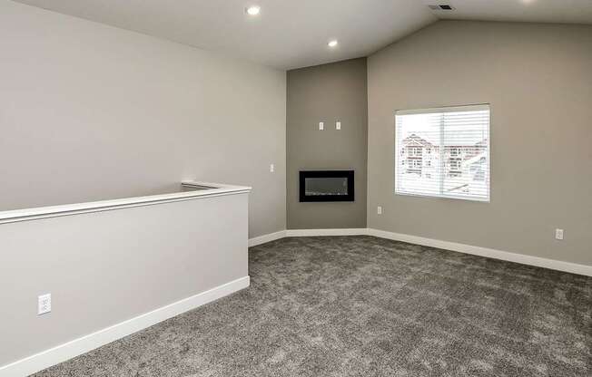 A room with a grey carpet and a window showing a house outside.