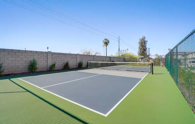 A tennis court with a green surface and a grey top.