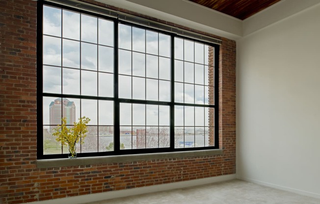 an empty room with a large window and a brick wall at Tindeco Wharf, Baltimore Maryland