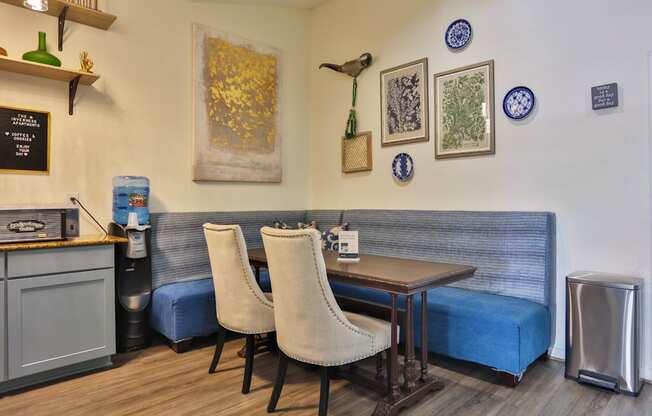 A resident lounge with a blue couch, wooden table, and two chairs at The Inverness Apartments in Houston, TX